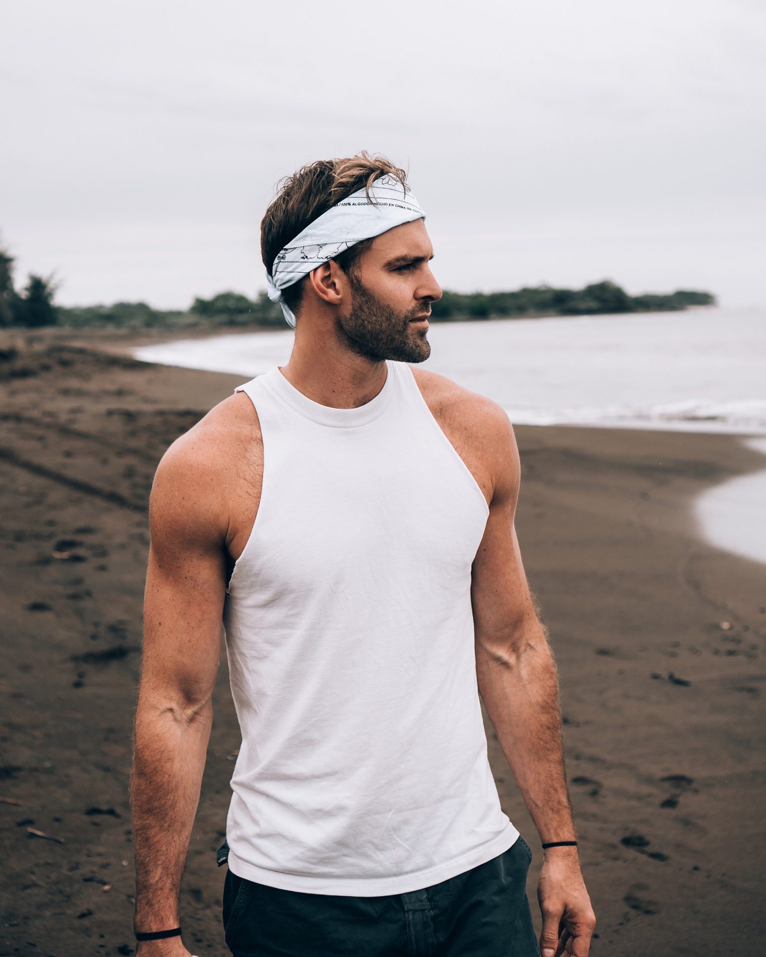 Guy on Beach Wearing White Bandanna, White Tank Top, and Jeans